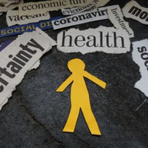 Figure of a person cut out of yellow paper surrounded by words torn from newspaper headlines.